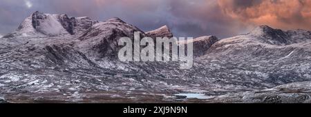 Sonnenaufgang über den Bergen von Assynt im Winter, Ben Mor Coigach, Beinn Tarsuinn, Sgurr an Fhidhleir und Beinn an Eoin mit Lochanan Dubha unten, Assyn Stockfoto