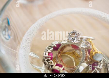Reinigung Vintage Schmuck Diamant Ring und Armband in Glas auf Holztischhintergrund Stockfoto