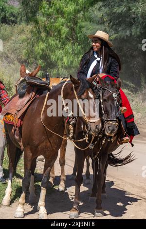 Ein weiblicher Gaucho in traditioneller Kleidung, der in Cachi, Argentinien reitet. Ein weiblicher Gaucho wurde traditionell „china“ genannt, ein indigener Quechua Stockfoto