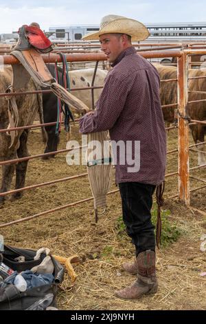 Ein Rodeo-Cowboy passt seine Bareback-Takelage an, bevor er in einem Rodeo in einer kleinen Stadt in Utah mit Bareback-Bronc-Fahrt fährt. Stockfoto