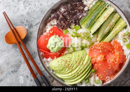 Japanische Sushi-Schüssel mit Lachs, Reis, Gemüse, Algen, Ingwer und Wasabi in Nahaufnahme auf dem Tisch. Horizontale Draufsicht von oben Stockfoto