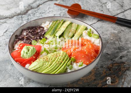 Japanische Sushi-Schüssel mit Lachs, Reis, Gemüse, Algen, Ingwer und Wasabi in Nahaufnahme auf dem Tisch. Horizontal Stockfoto