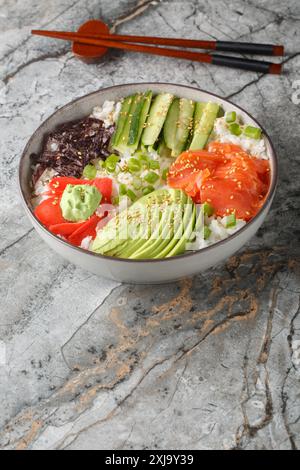 Sushi-Schüssel mit Lachs, Avocado, Gurke, weißem Reis, Sesam, ginger und Wasabi-Nahaufnahme auf dem Tisch. Vertikal Stockfoto