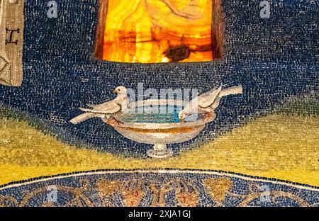 Detail eines farbenfrohen religiösen Mosaiks mit einem kleinen Brunnen, aus dem zwei Tauben trinken Stockfoto