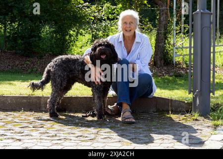 Europa, Luxemburg, Septfontaines, ältere Frau sitzt mit ihrem Haustier portugiesischer Wasserhund Stockfoto