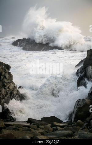 Mächtige Wellen krachen auf Meeresfelsen, stürmische Bedingungen mit großen Wellen auf dem Atlantik in Island, die auf den Klippen brechen Stockfoto