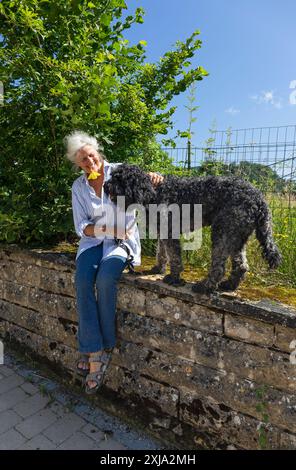 Europa, Luxemburg, Septfontaines, attraktive ältere Frau, die mit ihrem Haustier Portugiesischer Wasserhund spielt Stockfoto