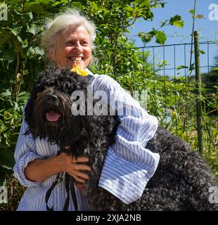 Europa, Luxemburg, Septfontaines, attraktive ältere Frau, die mit ihrem Haustier Portugiesischer Wasserhund sitzt Stockfoto