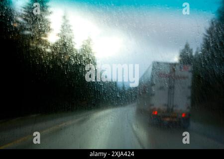 Semi-Lkw fahren bei starkem Regen auf einer interstate Highway durch Bäume, Snoqualmie Pass, WA, USA. Stockfoto