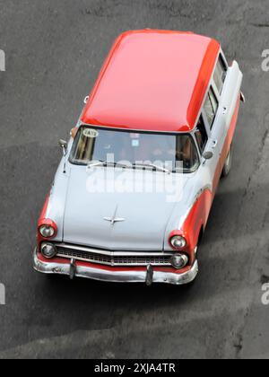Havanna, Kuba - 5. Juni 2015 - Oldtimer in Rot und weiß, der auf einer städtischen Straße fährt, von oben gesehen Stockfoto