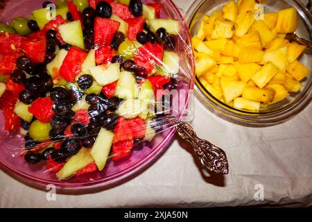 Obstsalate in Glasschüsseln, Blick von oben auf Beeren, geschnittene Melonen, Wassermelonen und Mango, Stockfoto