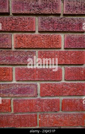 Nahaufnahme einer alten, tonroten Ziegelmauer, in einem laufenden Bindungsmuster mit Mörtel gelegt. Stockfoto