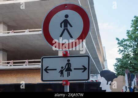 Nahaufnahme eines Verkehrszeichens mit Hinweis auf eine Fußgängerzone (rundes rot umrandetes Schild) über einem Hinweisschild für Fußgänger mit Kindern. Stockfoto