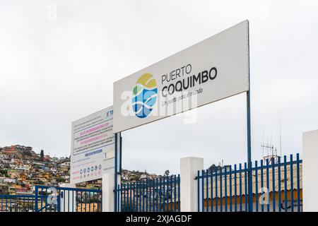 Coquimbo, Chile - 15. März 2019: Ein Schild, das den Eingang zu Puerto Coquimbo vor dem Hintergrund von Häusern am Hügel markiert. Stockfoto