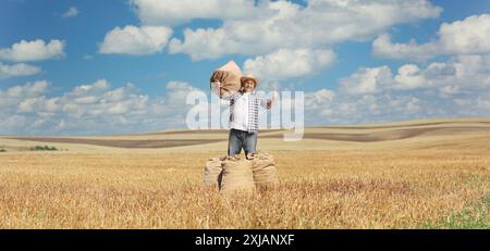 Ein Bauer trägt einen großen Sacksack auf der Schulter und drückt Daumen nach oben auf einem Weizenfeld Stockfoto