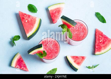 Frischer Wassermelonensaft mit Minzblättern in Gläsern auf blauem Hintergrund, Draufsicht. Süßer Sommer-Smoothie, Detox-Cocktail, Bio-gesundes Getränk. Stockfoto