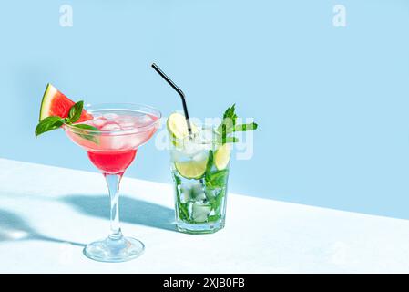 Trendiges Mojito und rosa Margarita Cocktail Drink mit Wassermelone, Minze und Eis auf hellblauem Hintergrund, Sonnenlicht, Kopierraum. Kreativer Sommercocktail Stockfoto