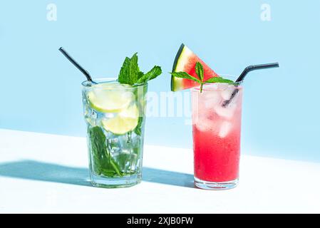 Trendiges Mojito und rosafarbenes Cocktailgetränk mit Wassermelone, Minze und Eis auf hellblauem Hintergrund, Sonnenlicht, Kopierraum. Kreative Sommer-Cocktailparty, Be Stockfoto