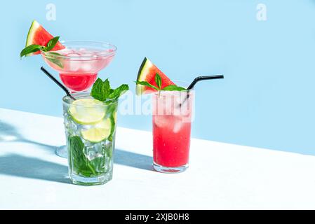 Trendige Sommer-Cocktail-Drinks mit Wassermelone, Limette, Minze und Eis auf blauem Hintergrund, Kopierraum. Cocktailparty im Sommer, Strandbar-Konzept. Mojiho A. Stockfoto