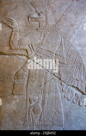 Alabaster-Relief eines adlerköpfigen geflügelten Apkallu mit Eimer und Kegel für religiöse Rituale. Schloss Ashurnasirpal II. Pergamonmuseum, Berlin. Stockfoto