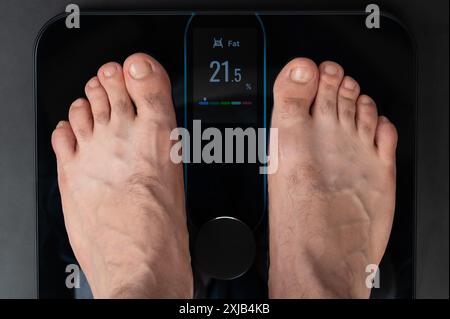 Überprüfen des Fettspiegels mit einer elektronischen Waage, die auf dem Gewicht steht Stockfoto
