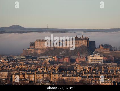 12.18.2021, Edinburgh, Schottland: Edinburgh Castle mit Wohngebäuden im Vordergrund und Nebelwolkenumkehr über der Mündung des Firth of Forth Stockfoto