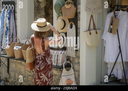 Eine junge Frau, die im Souvenirladen einen Strohsommerhut auswählt Stockfoto