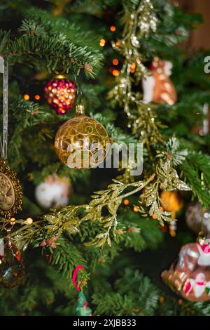 Eine Nahansicht eines Weihnachtsbaums, der mit farbenfrohen Ornamenten verziert ist, einschließlich einer Goldkugel mit komplizierten Details Stockfoto