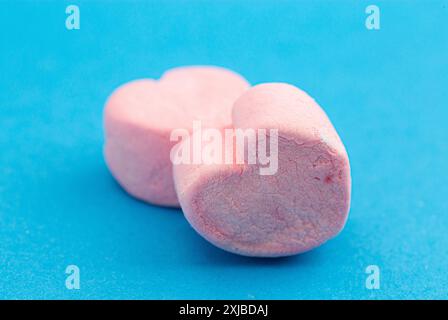 Knusprige gefriergetrocknete Marshmallows in der Form der Liebesherzen auf blauem Hintergrund Stockfoto