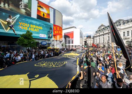 London, Großbritannien. 17. Juli 2024. Eine riesige Flagge wird durch den Piccadilly Circus getragen, während Zehntausende britische Muslime an dem Martyrium von Hussain, dem Enkel des Propheten Mohammed, an dem zehnten Tag auf Arabisch, erinnern. Dieses friedliche Ereignis wird weltweit jährlich gefeiert, bei dem Menschen in Erinnerung gehen. In der Hauptstadt führte der Weg von Marble Arch nach Whitehall. Quelle: Stephen Chung / Alamy Live News Stockfoto