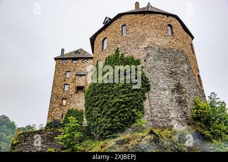 Runder und quadratischer Steinturm mit mehreren Fenstern auf der Burg Reinhardstein auf dem Hügel, Blick aus der flachen Perspektive, Mauer mit Kletterpflanzen, Warche Stockfoto