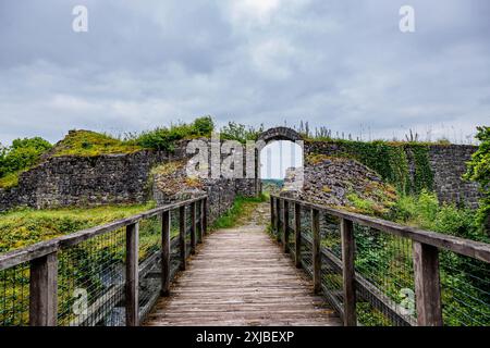 Hölzerne Brücke, die zu einem bogenförmigen Tor am Schloss Logne führt, alte Steinmauer vor grauem wolkenbedecktem Himmel, bewölkter Tag in Ferrieres, Belgien Stockfoto