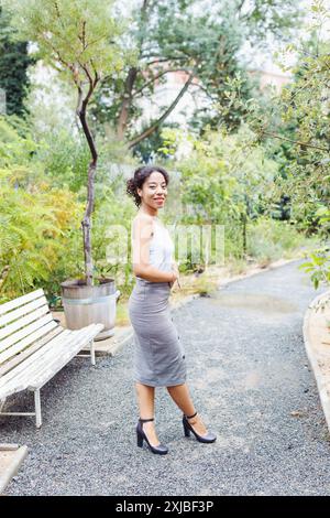 Stilvolle junge Frau im modernen Outfit posiert in einem städtischen botanischen Garten Stockfoto