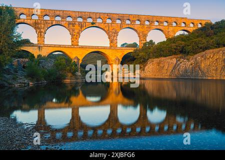 Ein Sommersonnenaufgang am Pont du Gard, einem römischen Aquädukt über dem Gardon River, der später zu einer Brücke ausgebaut wurde. Die Struktur befindet sich in der Nähe des to Stockfoto