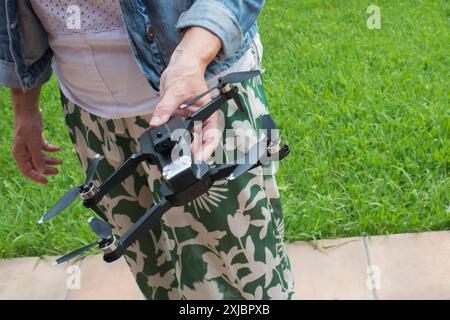 Unerkennbare kaukasische Frau, die draußen einen Quadcopter hält. Zwanglose Kleidung, echt Stockfoto