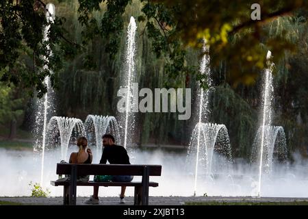 Bukarest, Rumänien. Juli 2024. Ein Paar sitzt am 17. Juli 2024 auf einer Bank im Schatten eines Parks in Bukarest, Rumänien. Die rumänische nationale Meteorologische Verwaltung (ANM) hat ihre roten und orangen Hitzewarnungen bis Mittwoch verlängert, was das gesamte Land während einer andauernden Hitzewelle betrifft. Quelle: Cristian Cristel/Xinhua/Alamy Live News Stockfoto