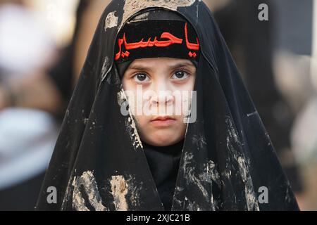 Karbala, Irak. Juli 2024. Ein irakisches schiitisches muslimitisches Kind schmierte ihr Gesicht mit Schlamm, während er an Trauerritualen während einer religiösen Prozession vor dem Ashura-Tag in der Nähe des Heiligtums von Imam Hussein teilnahm. Muharram gilt als ein Monat der Trauer und Erinnerung an schiitische Muslime auf der ganzen Welt, in dem sie dem Martyrium des Enkels des islamischen Propheten Mohammad, Hussein ibn Ali, gedenken, der in der Schlacht von Karbala im 7. Jahrhundert getötet wurde. (Foto: Ismael Adnan/SOPA Images/SIPA USA) Credit: SIPA USA/Alamy Live News Stockfoto