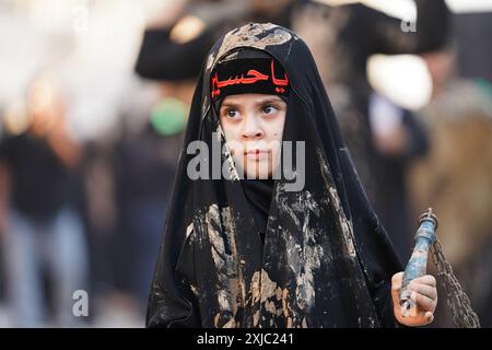 Karbala, Irak. Juli 2024. Ein irakisches schiitisches muslimitisches Kind schmierte ihr Gesicht mit Schlamm, während er an Trauerritualen während einer religiösen Prozession vor dem Ashura-Tag in der Nähe des Heiligtums von Imam Hussein teilnahm. Muharram gilt als ein Monat der Trauer und Erinnerung an schiitische Muslime auf der ganzen Welt, in dem sie dem Martyrium des Enkels des islamischen Propheten Mohammad, Hussein ibn Ali, gedenken, der in der Schlacht von Karbala im 7. Jahrhundert getötet wurde. (Foto: Ismael Adnan/SOPA Images/SIPA USA) Credit: SIPA USA/Alamy Live News Stockfoto