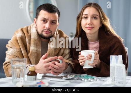 Frau und Mann in Plaids gehüllt mit Symptomen von Kälte zu Hause Stockfoto
