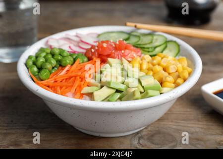 Leckerer Salat mit Lachs und Gemüse auf Holztisch, Nahaufnahme Stockfoto