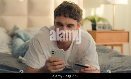Mann liegend Bett Handy Smartphone Technologie online bestellen Kauf Käufer Kunde Kunde Bank Kreditkarte Zahlungstransaktion Geldfinanzierung Stockfoto