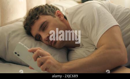 Junger Mann, der auf dem Bett liegt, Schlafzimmer umdrehen Wochenendferien Entspannungsheim im Inneren gemütliche Ruhe schlafen früh morgens Bettzeug Nickerchen komfortable Träume faul Stockfoto