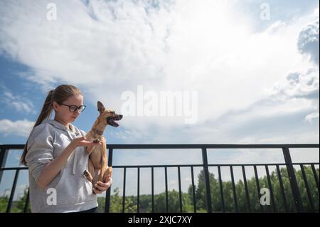 Junge kaukasische Frau, die einen kleinen Hund in der Hand hält. Stockfoto