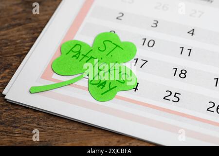 Papier Kleeblatt mit den Worten ST. PATRICKS TAG und Kalender auf Holzhintergrund Stockfoto