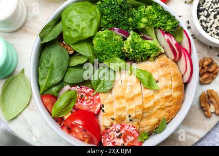 Gesunde Mahlzeit. Köstliches Hühnchen, Gemüse und Spinat in einer Schüssel auf dem Tisch, flach gelegt Stockfoto