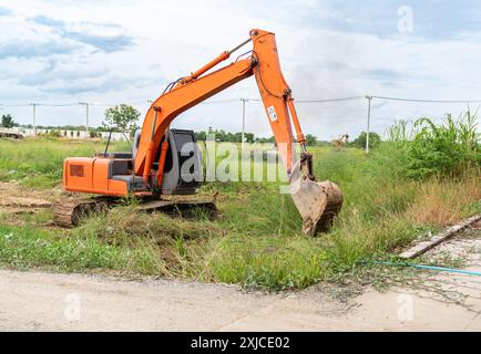 Schaufelbagger bei der Arbeit auf dem Land in einem privaten Hof. Das Graben des Bodens, die Rodung von Land und die Landschaftsgestaltung erfolgt mit einem Exkuvator. Stockfoto