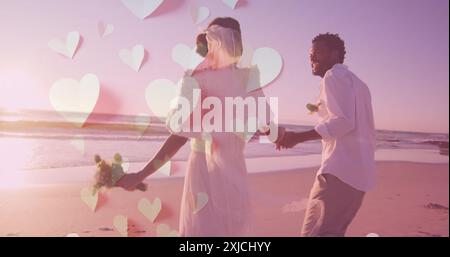 Bild von Herzen über glückliche, vielfältige, gerade verheiratete Paare, die am Strand am Meer laufen Stockfoto