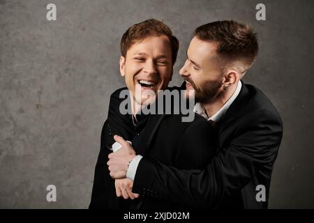 Zwei Männer in Anzügen umarmen und lachen zusammen. Stockfoto