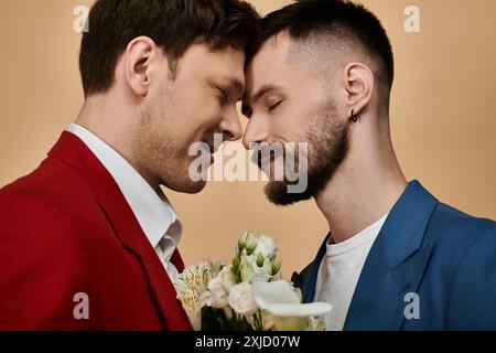 Zwei Männer in eleganten Anzügen teilen einen liebevollen Moment, ihre Stirn berührt. Stockfoto