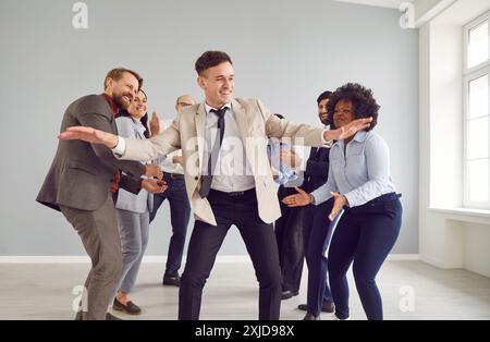 Glückliche Geschäftsleute in Bürokleidung, die drinnen tanzen und Spaß haben. Stockfoto